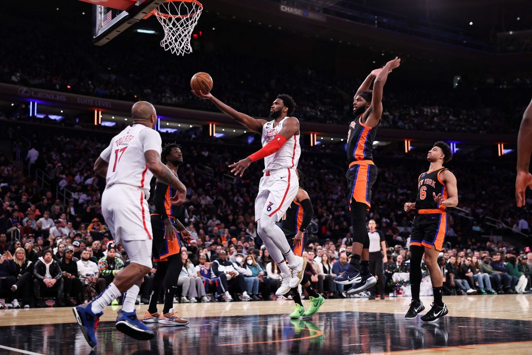 Joel Embiid (tengah) dari Philadelphia 76ers melakukan lemparan 'layup' saat timnya menghadapi New York Knicks di Madison Square Garden, Minggu (25/12). 