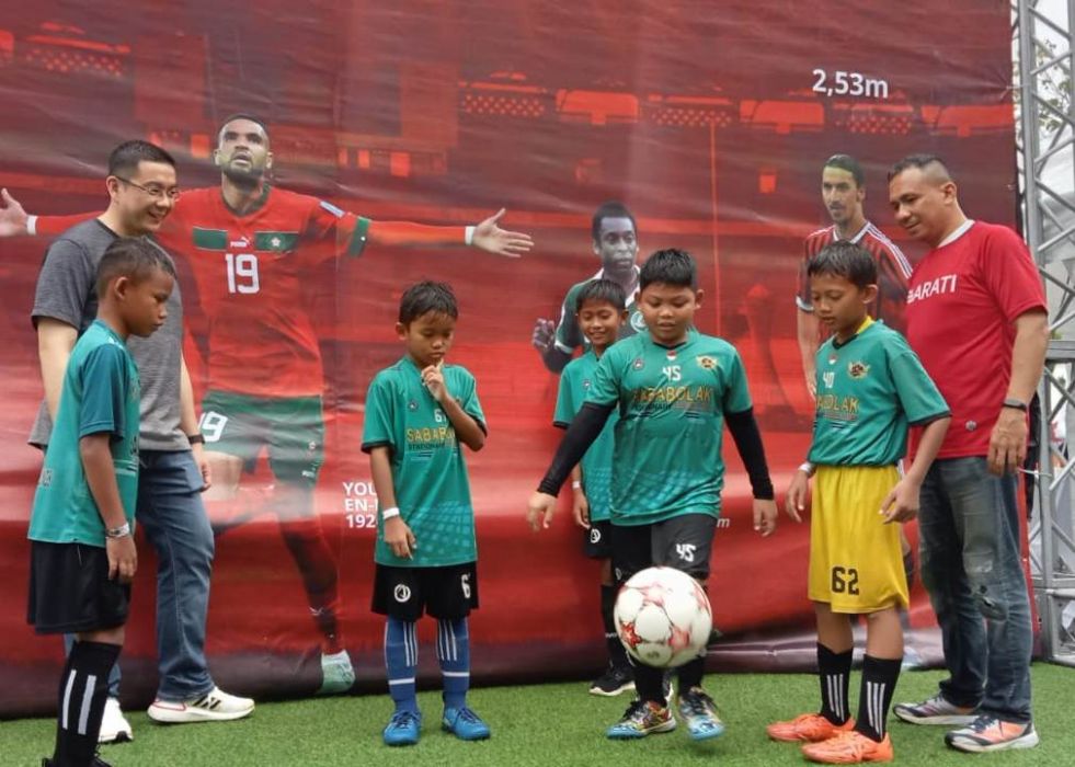 CEO Tays Bakers, Alexander Anwar (kiri) dan CEO Bangga Merah Putih Mendunia, Krisna Marsis (kanan) bersama anak-anak dari salah satu sekolah sepak bola.