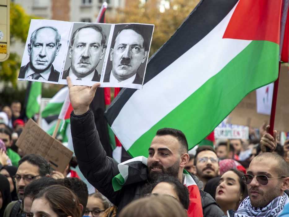 Para pengunjuk rasa memegang bendera nasional Palestina dan potret Perdana Menteri Israel Benjamin Netanyahu yang berubah menjadi pemimpin Nazi Jerman Adolf Hitler dalam unjuk rasa di Brussel, Belgia, 22 Oktober 2023. (AFP/Nicolas Maeterlinck)