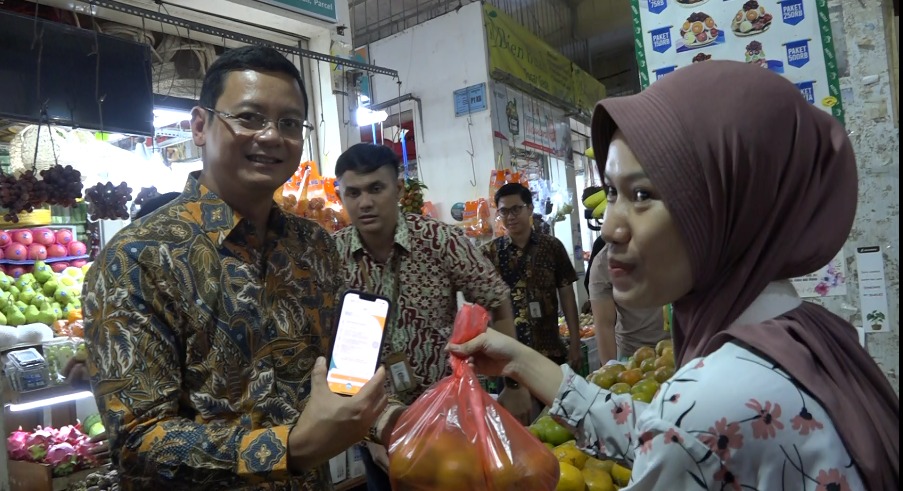 SEVP Digital Banking Saut Parulian Saragih (kiri) menggunakan BSI Mobile untuk transaksi QRIS di salah satu kios buah di Pasar Gede Solo, Surakarta, Senin (15/1).