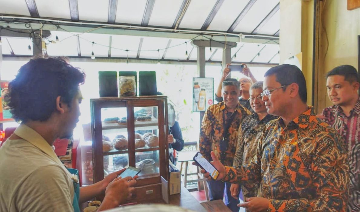 SEVP Digital Banking Saut Parulian Saragih (kanan) menggunakan BSI Mobile untuk transaksi QRIS di salah satu warung kopi di Pasar Gede Solo, Surakarta, Senin (15/1).