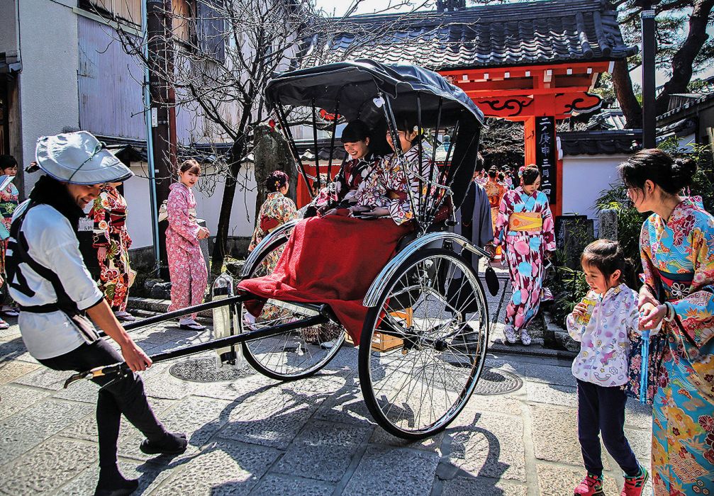 Wisatawan mengenakan kimono menaiki Jinrikisha di Kyoto, Jepang.