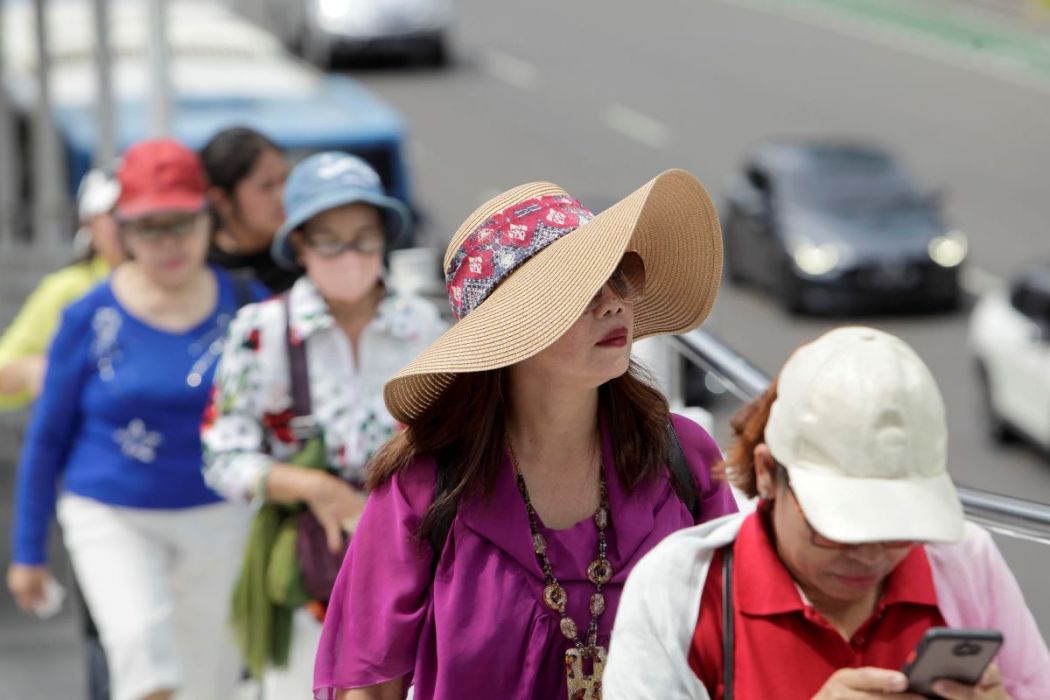 Warga menggunakan topi untuk melindungi diri dari terik sinar matahari.