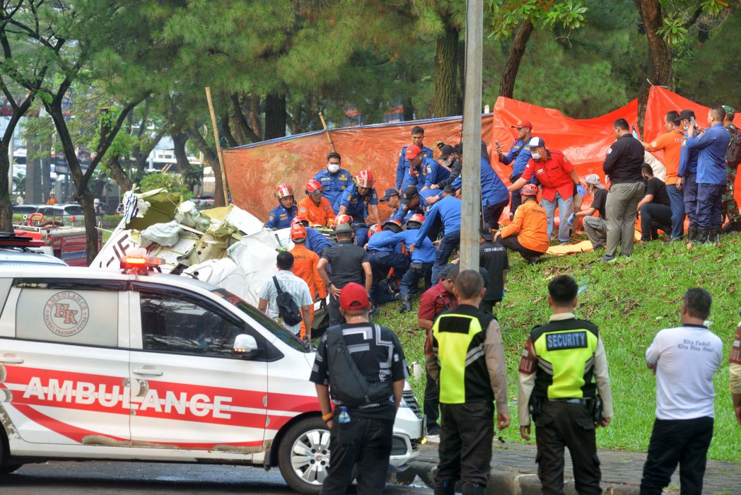 Petugas berusaha mengevakuasi korban pesawat jatuh di BSD, Tangerang Selatan, Minggu (19/5/2024). (MI/Agung Wibowo)