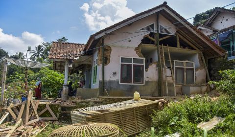 Warga membersihkan puing bangunan rumahnya yang roboh terdampak gempa di Desa Sukamulya, Kabupaten Ciamis, Jawa Barat, Minggu (28/4).